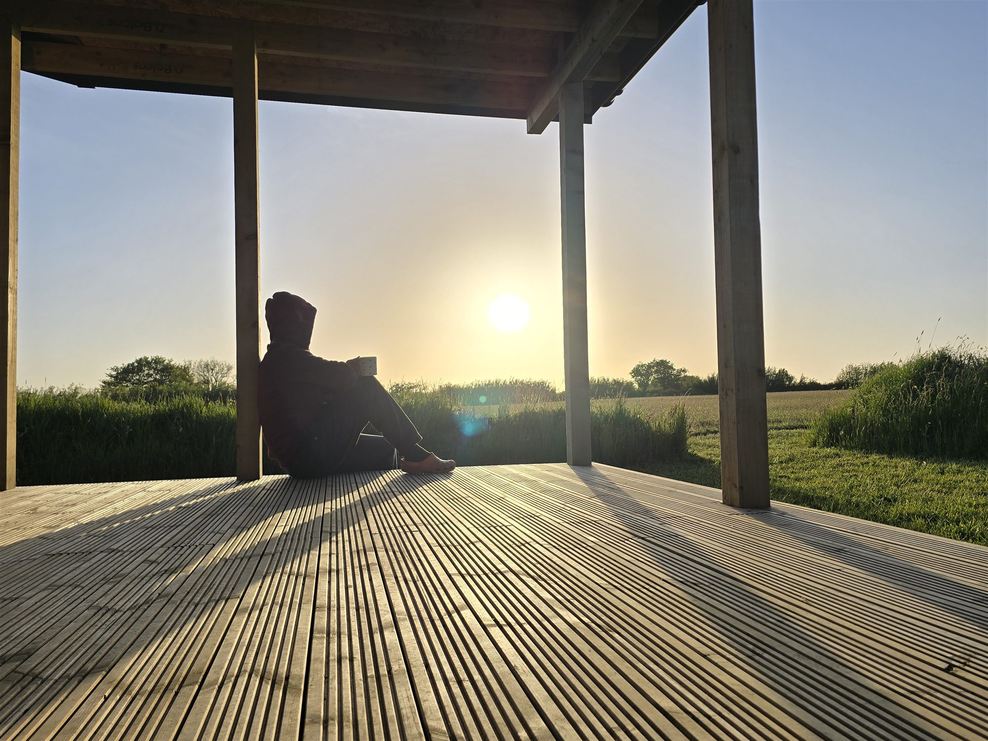 A guest sitting quietly on a covered lodge deck at sunset.